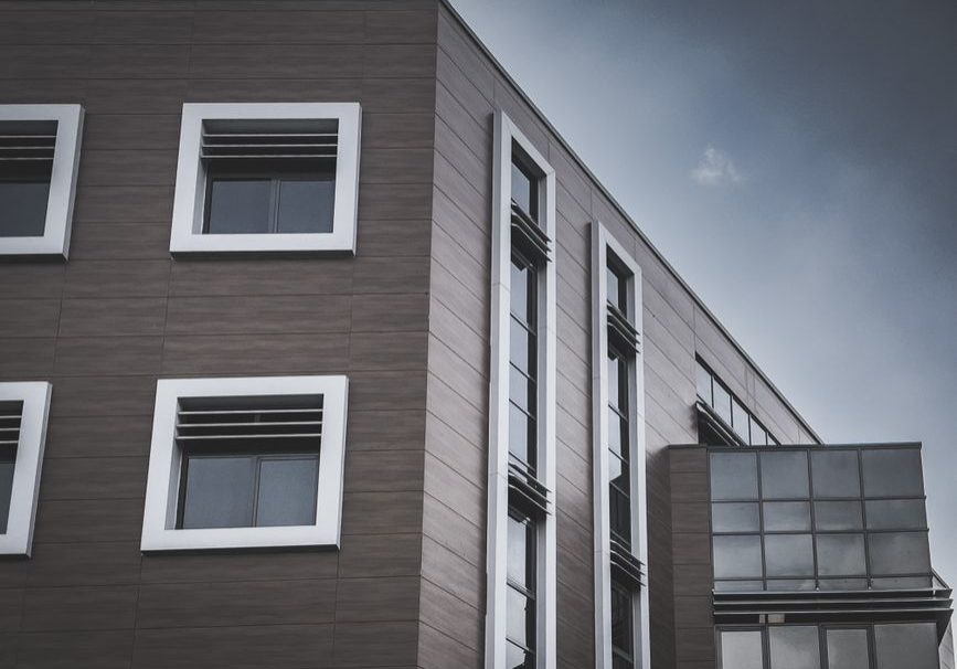 A modern apartment building with a geometric facade, featuring glass and clean lines under a clear sky.